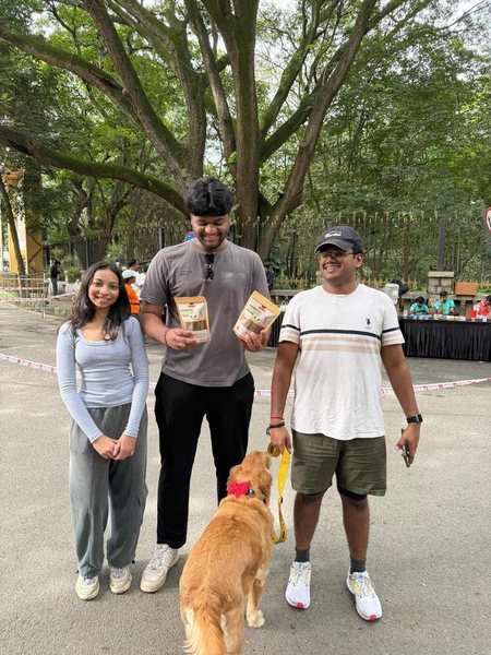 Three friends at the park with a Golden Retriever and two packs of prebiotic sticks